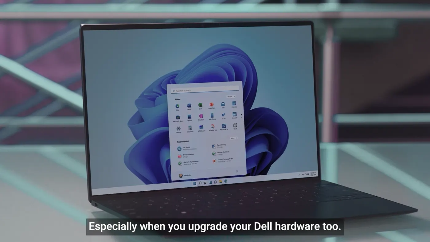 A Dell laptop open on a glass table showing the Windows 11 start menu, subtitled especially when you upgrade your Dell hardware too